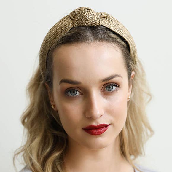 Woman wearing a natural rattan headband with a plain background