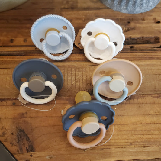 A collection of various colored pacifiers laid out on a wooden surface.